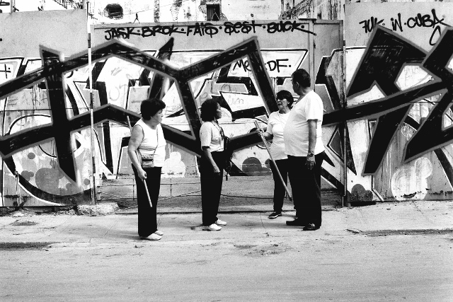 Black and white image of a group of people exercising with wooden poles. 